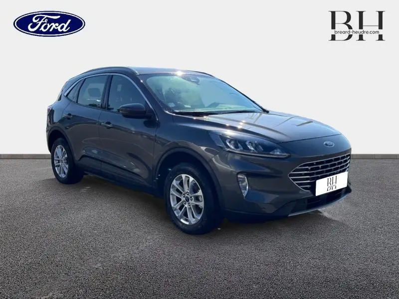 Ford Kuga hybride rechargeable gris Magnetic en vue 3/4 avant, avec calandre distinctive et jantes alu visibles.