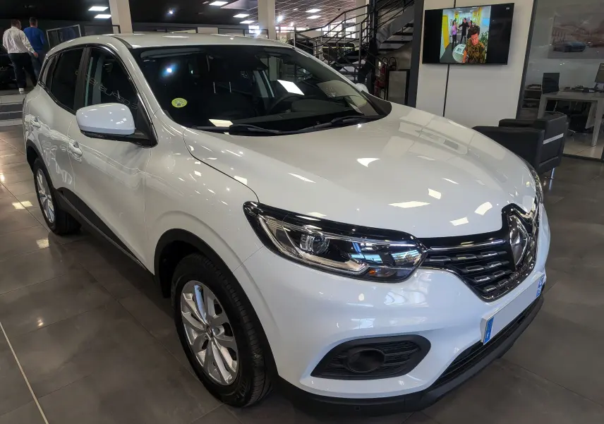 Renault Kadjar Blanc Glacier en 3/4 avant droit dans un showroom, avec jantes alliage et calandre noire brillante.