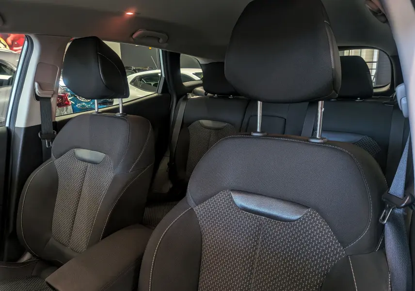 Vue intérieure centrée sur les sièges avant en tissu noir du Renault Kadjar, avec la carrosserie blanche visible à l'extérieur.