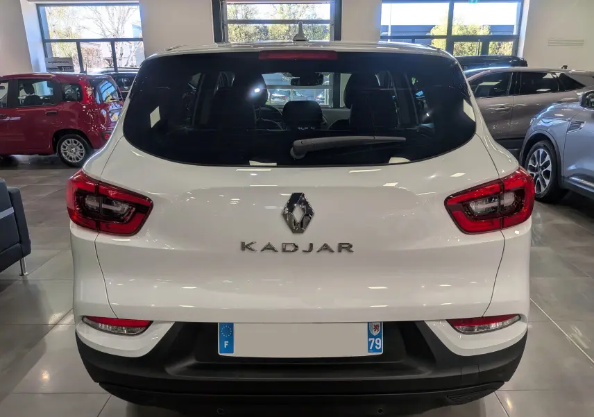 Vue arrière d'un Renault Kadjar blanc Glacier 2021 dans un showroom, avec feux arrière rouges et lunette arrière teintée.