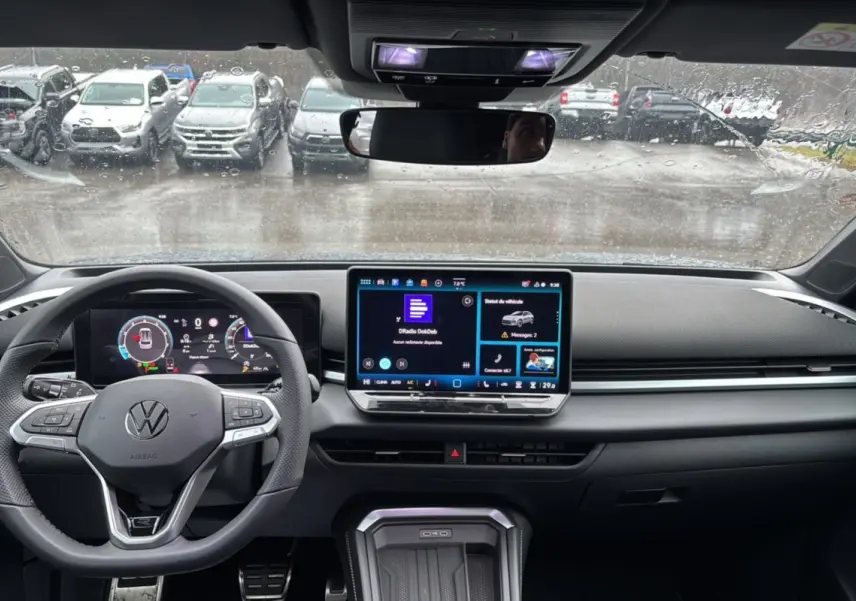 Vue intérieure frontale du tableau de bord du Volkswagen T-Roc gris loup avec écran tactile et volant multifonctions.