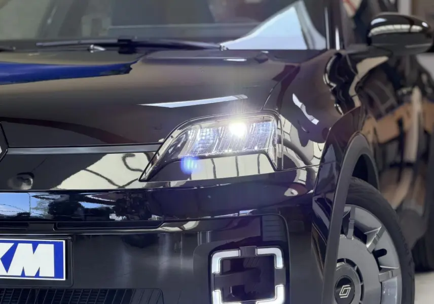 Vue 3/4 avant droit de la Renault R5 E-Tech électrique 2026 en Noir Étoilé avec phares et feux LED allumés.