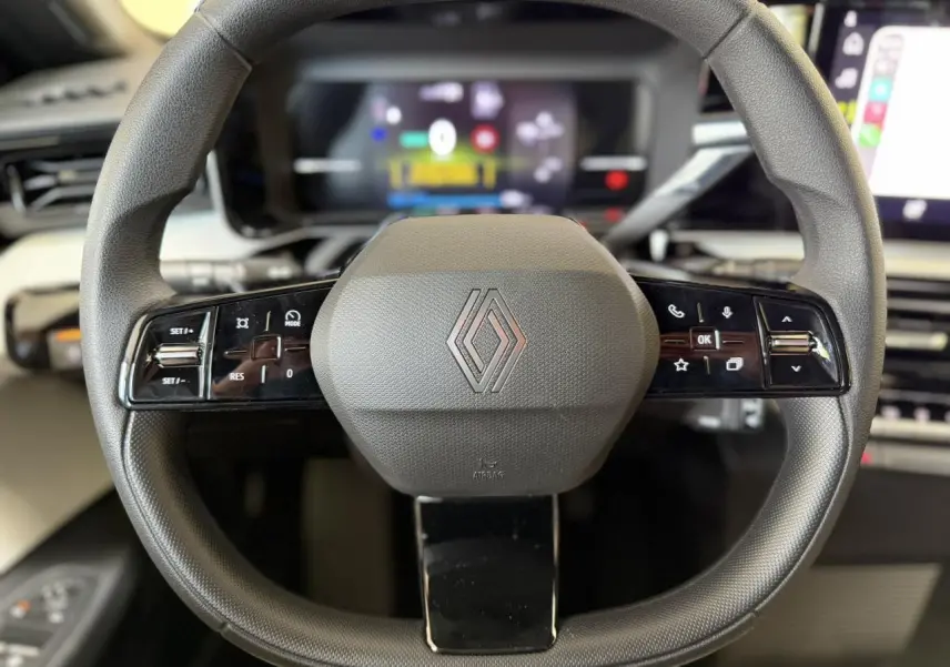 Vue rapprochée du volant noir grainé multifonction de la Renault R5 E-Tech 2026 avec logo central et commandes intégrées.