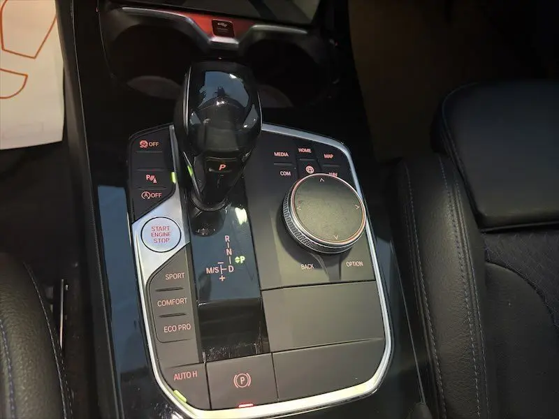 Gros plan sur la console centrale noire brillante de la BMW Série 1 118D avec levier de vitesse automatique et commandes multimédia.