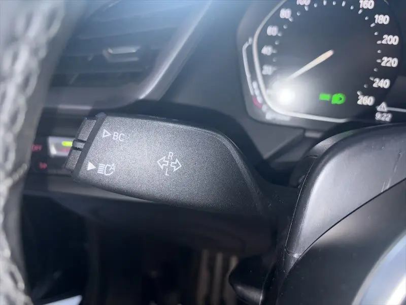 Gros plan sur la manette de clignotant noire à gauche du volant dans une BMW Série 1 noire métal de 2020.