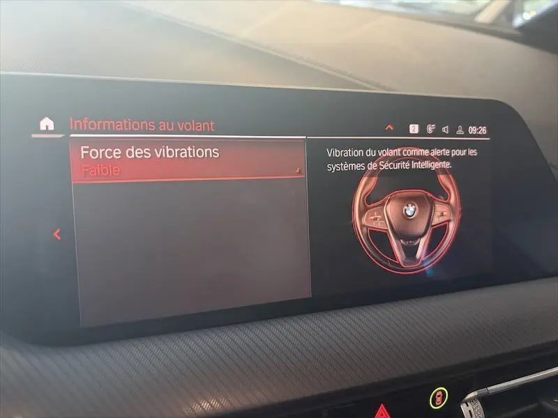 Écran central intérieur de BMW Série 1 affichant les informations sur la force des vibrations du volant en mode faible.