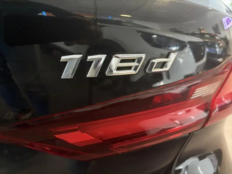 Gros plan sur l'arrière droit noir métallisé de la BMW Série 1 avec le badge 118d et le feu arrière rouge.