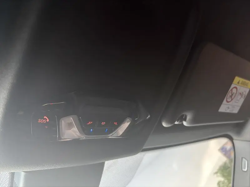 Vue intérieure du plafonnier avec commandes éclairage et bouton SOS sur BMW Série 1 noire.