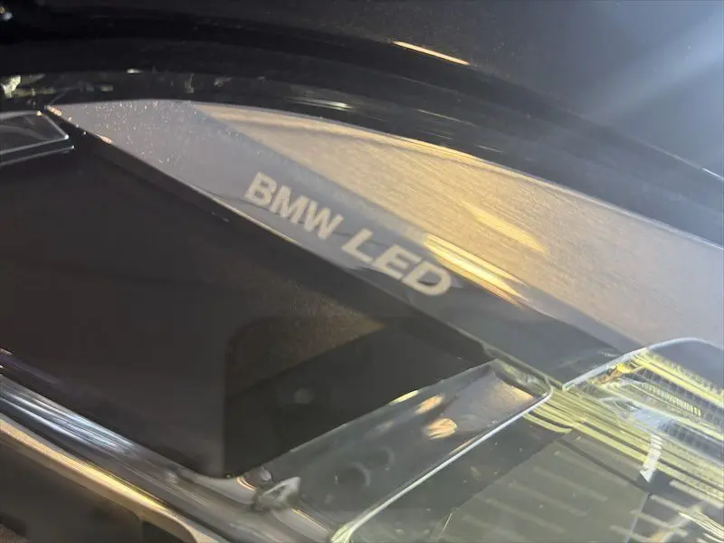 Gros plan sur le phare avant droit noir métal de la BMW Série 1 118D avec inscription BMW LED visible.