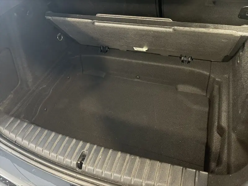 Coffre ouvert vu de dessus d'une BMW Série 1 noire, montrant un espace de rangement propre et vide.