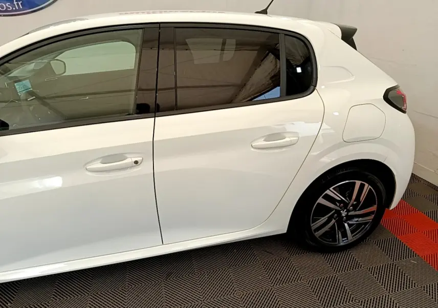 Vue latérale droite d'une Peugeot 208 blanche 2021 avec jantes alliage et vitres teintées.