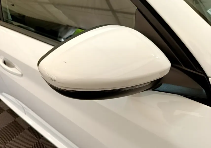 Rétroviseur droit blanc de la Peugeot 208 PureTech 100 S&S Allure Business vue en gros plan sur porte blanche.