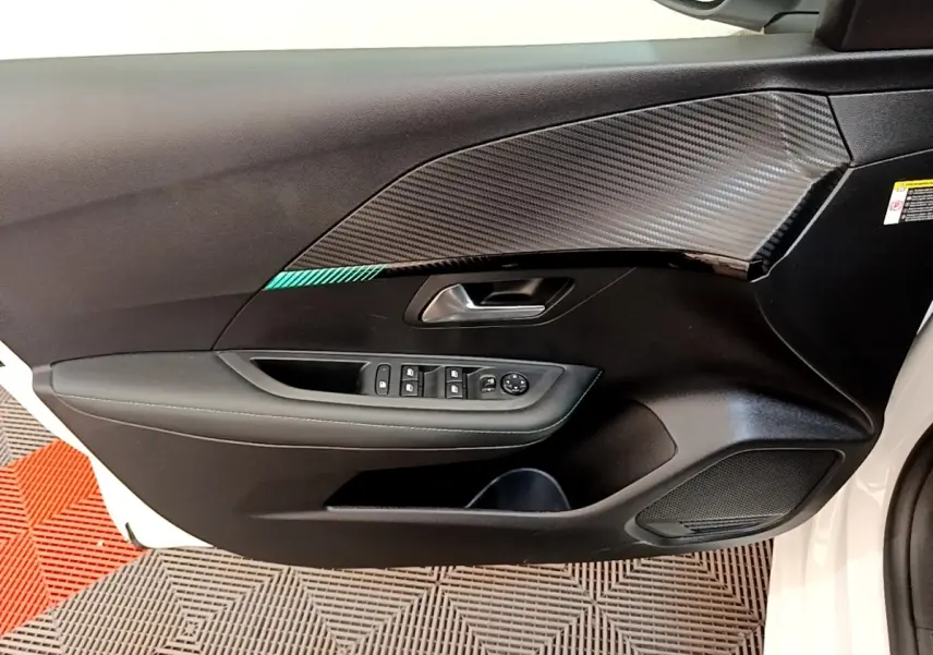 Vue rapprochée de la porte avant gauche blanche du Peugeot 208 avec habillage noir et insert effet carbone.
