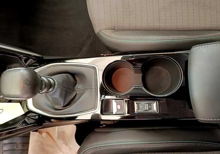 Vue plongeante sur la console centrale noire de la Peugeot 208 blanche, avec levier de vitesse manuel et porte-gobelets.