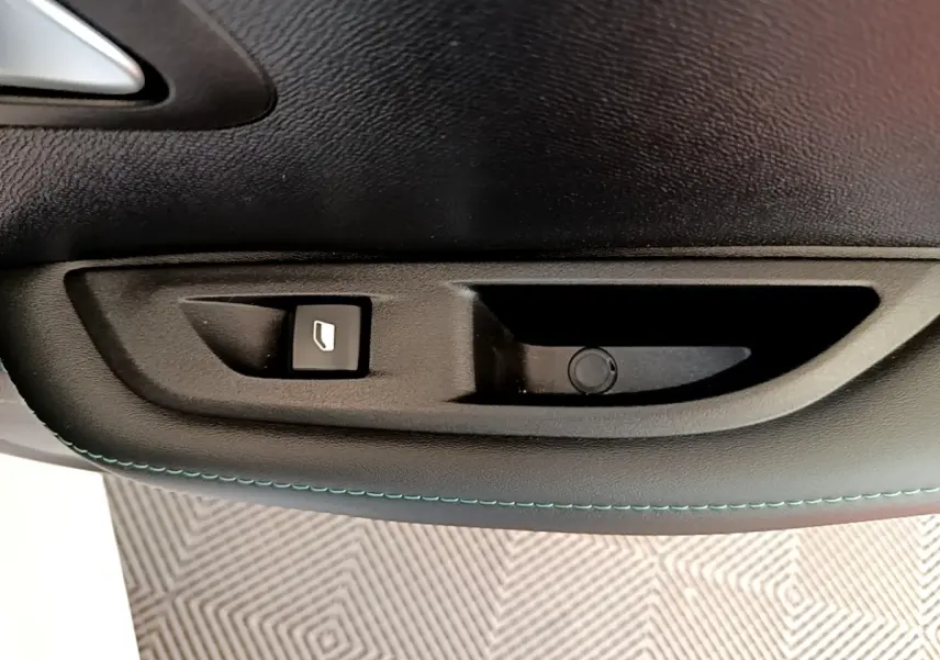Gros plan sur la commande de lève-vitre côté gauche d’une Peugeot 208 blanche, finition Allure Business.