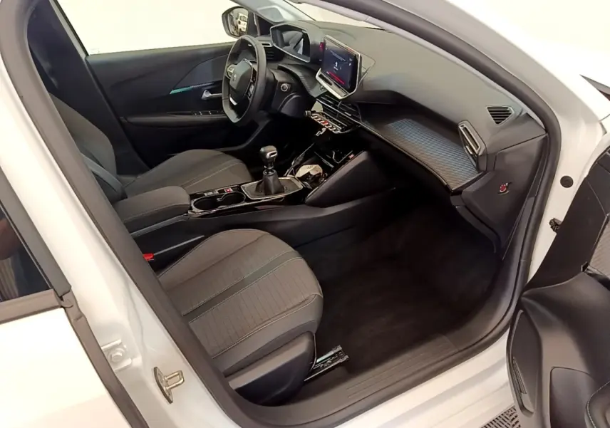 Vue intérieure côté conducteur de la Peugeot 208 blanche, mettant en valeur le tableau de bord et l’écran tactile 10 pouces.