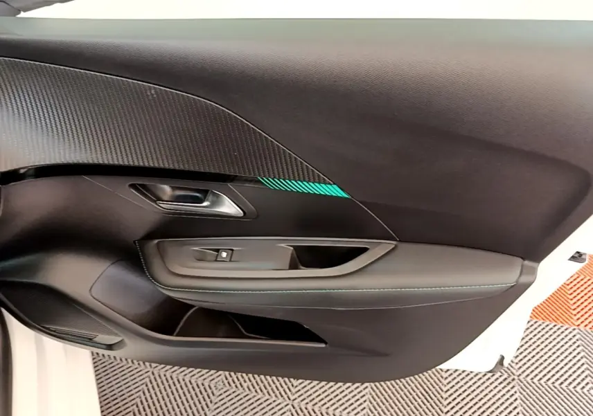 Vue intérieure côté gauche de la porte avant d'une Peugeot 208 blanche avec insert décoratif et surpiqûres bleues.