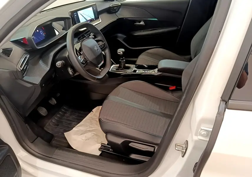 Intérieur avant droit d’une Peugeot 208 blanche, avec tableau de bord numérique et écran tactile central visible.