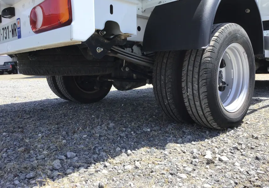 Gros plan sur les roues jumelées arrière droite du Renault Master Châssis Cabine blanc avec benne, vue basse.