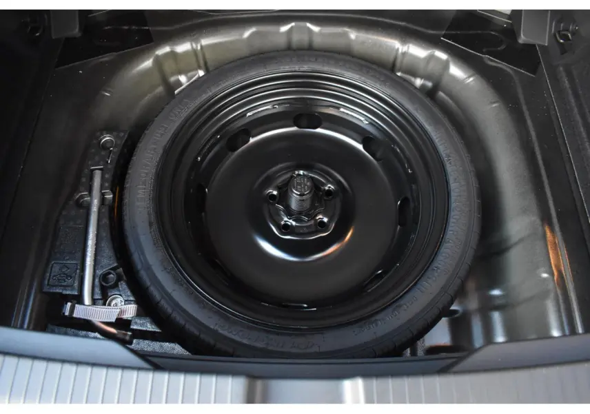 Gros plan sur la roue de secours à encombrement réduit noire dans le coffre du Volkswagen T-Roc 2025.