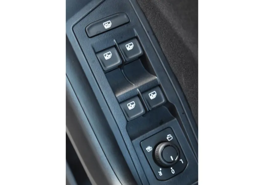 Gros plan sur les commandes de lève-vitres et réglage des rétroviseurs côté conducteur du Volkswagen T-Roc noir.