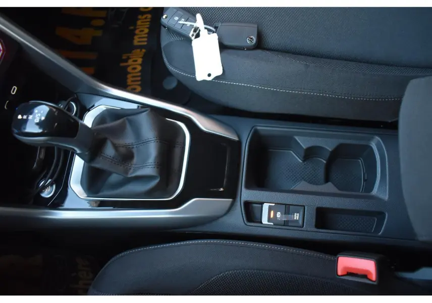 Vue intérieure centrée sur la console centrale et levier de vitesse du Volkswagen T-Roc 2025 avec sellerie noire.