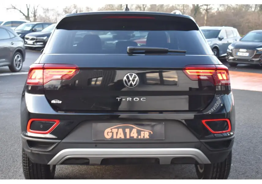 Vue arrière d'un Volkswagen T-Roc noir Grenadilla Metallic avec feux LED et détails rouges sur le pare-chocs.