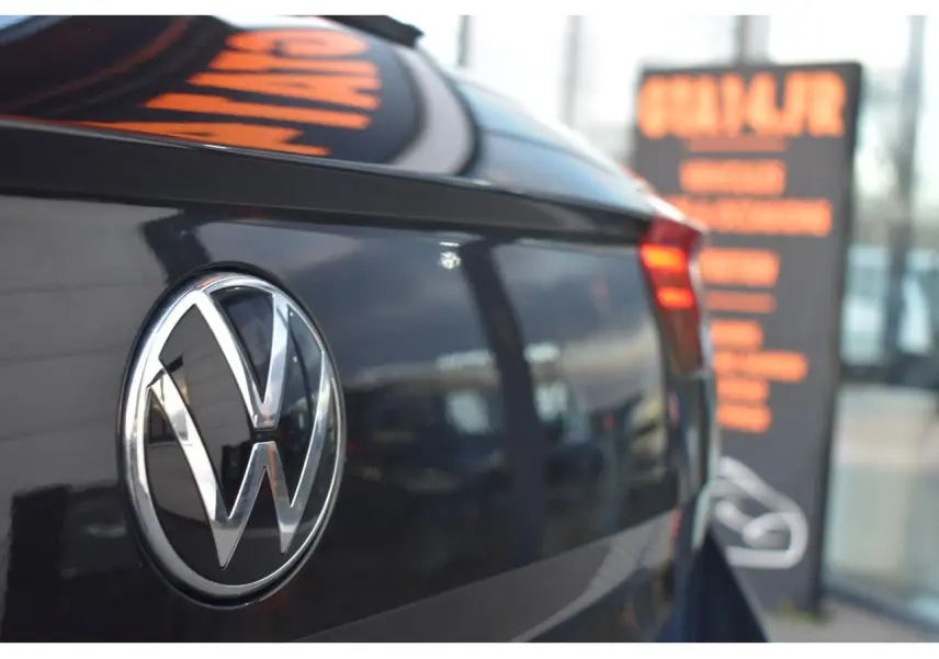 Gros plan sur l'arrière droit d'un Volkswagen T-Roc 2025 noir métallisé avec logo VW et feu arrière LED allumé.
