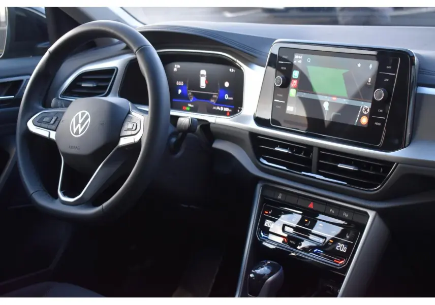 Vue intérieure du tableau de bord du Volkswagen T-Roc 2025, avec volant multifonction et écran tactile central.