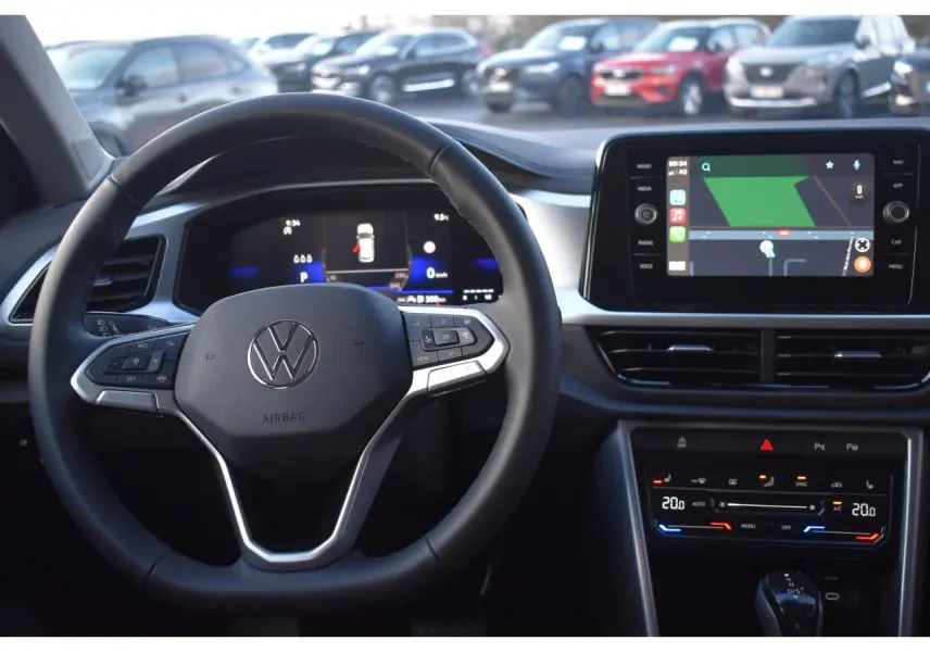 Vue intérieure centrée sur le volant Volkswagen T-Roc avec tableau de bord digital et écran tactile multimédia.