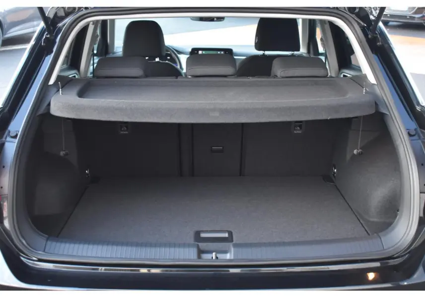 Coffre ouvert vu de l'arrière d'un Volkswagen T-Roc 2025 noir Grenadilla, avec cache-bagages et sièges arrière visibles.