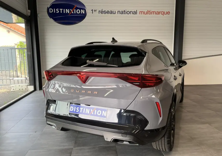 Vue 3/4 arrière droite d'un CUPRA Formentor gris clair avec signature lumineuse arrière Tri-LED et double sortie d'échappement noire.