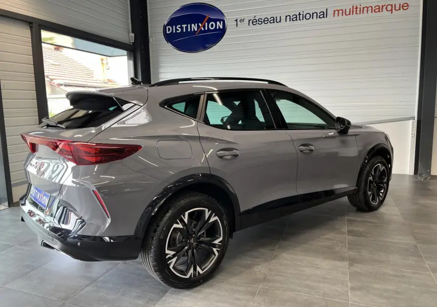 Vue 3/4 arrière droite du CUPRA Formentor gris clair avec jantes alliage 18'' et toit ouvrant panoramique en showroom.