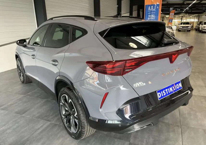 Vue 3/4 arrière droite d’un CUPRA Formentor gris clair avec bandeau lumineux arrière et jantes alliage noires.