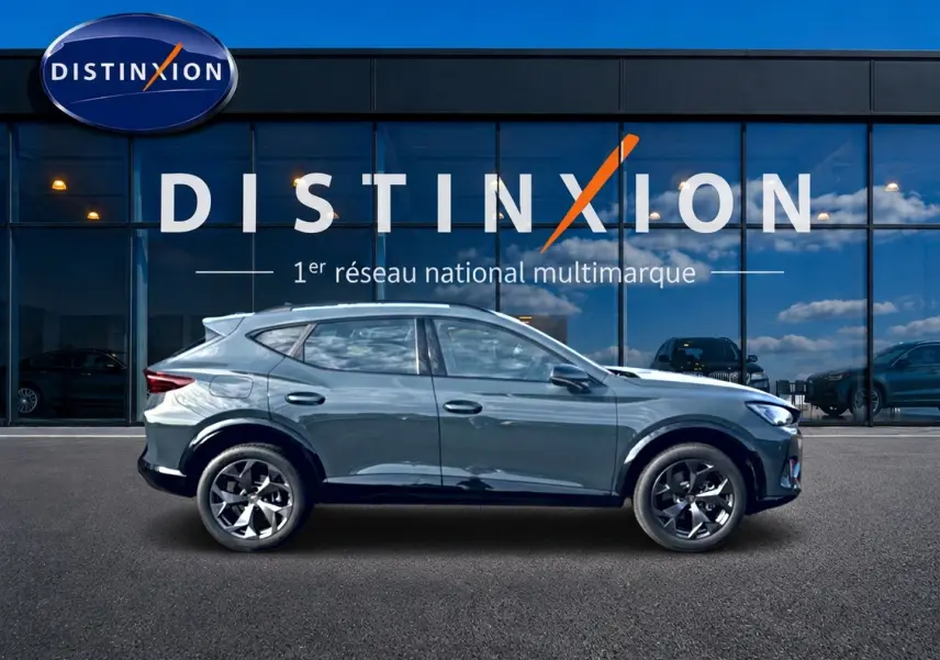 Vue de profil droit du CUPRA Formentor 1.5 etsi hybrid bleu fjord avec jantes 18 pouces devant une vitrine Distinxion.