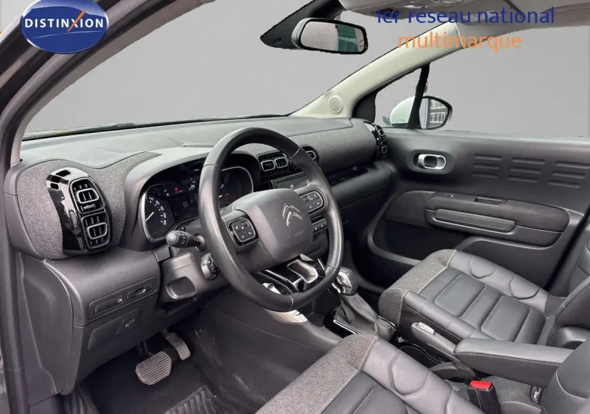Vue intérieure côté conducteur de la Citroën C3 Aircross gris platinium, avec tableau de bord et sièges en tissu et cuir.