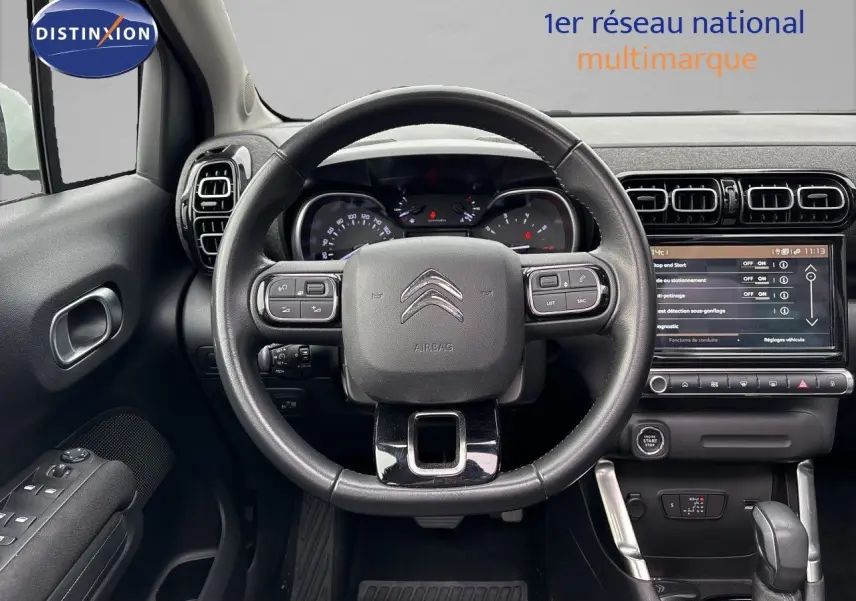 Vue intérieure centrée sur le volant noir et le tableau de bord numérique d'une Citroën C3 Aircross gris platinium.
