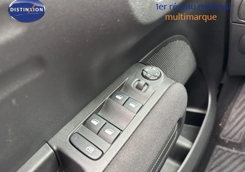Gros plan sur les commandes des vitres électriques côté conducteur d'une Citroën C3 Aircross gris platinium, intérieur noir.