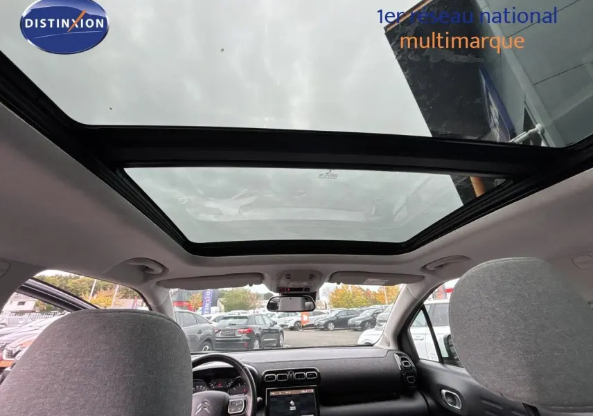 Vue intérieure avant du Citroën C3 Aircross gris platinium 2021, mettant en valeur le toit panoramique et le tableau de bord.