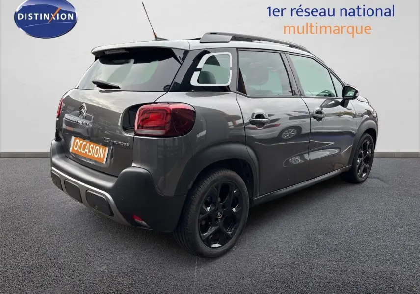 Vue 3/4 arrière droite d'une Citroën C3 Aircross Shine gris platinium avec jantes noires et toit noir.