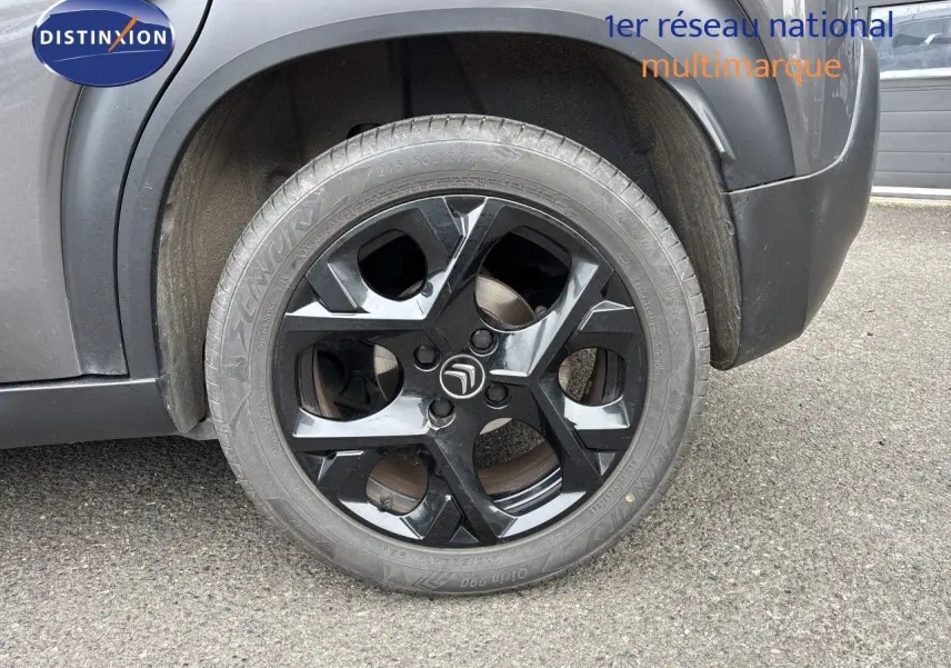 Gros plan sur la roue arrière droite noire brillante du Citroën C3 Aircross gris platinium, avec logo Citroën central.