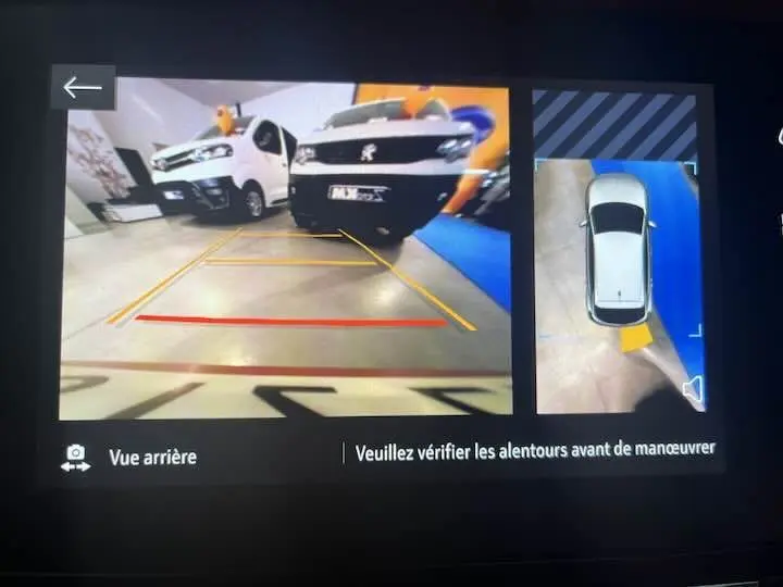 Vue arrière de l'Opel Corsa rouge Kardio avec caméra de recul et affichage des lignes de guidage au parking.