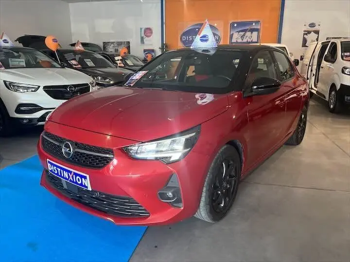 Opel Corsa rouge Kardio vue 3/4 avant droit en showroom avec toit noir et jantes noires.