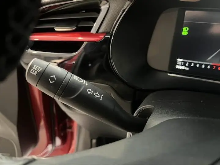 Gros plan sur le commodo de clignotant à gauche dans l'habitacle rouge Kardio d'une Opel Corsa 2021.