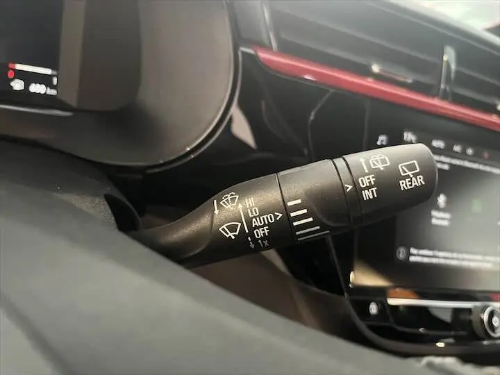 Le levier de commande des essuie-glaces dans l'habitacle de l'Opel Corsa rouge Kardio, vue rapprochée côté conducteur.