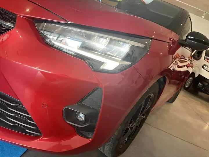 Gros plan sur l'avant droit de l'Opel Corsa rouge Kardio, mettant en valeur ses phares LED et sa calandre noire.