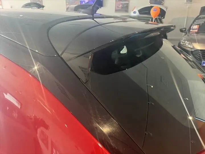Toit noir brillant et aileron arrière sur une Opel Corsa rouge Kardio vue en gros plan côté arrière droit.