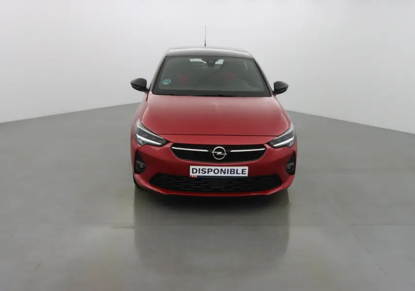 Vue frontale d'une Opel Corsa rouge Kardio avec calandre noire et phares LED allumés dans un studio blanc.