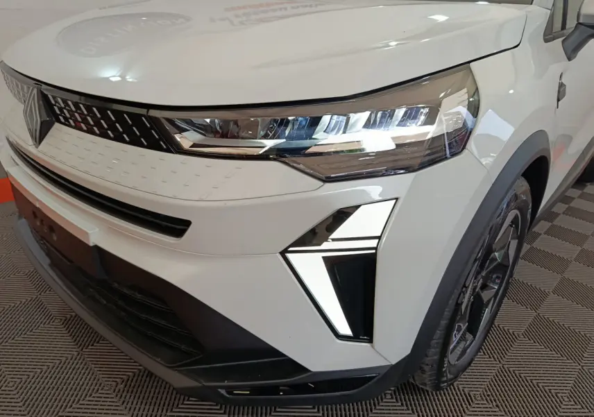 Gros plan sur l'avant droit blanc du Renault Captur 2025 avec phares LED et calandre moderne noire et blanche.