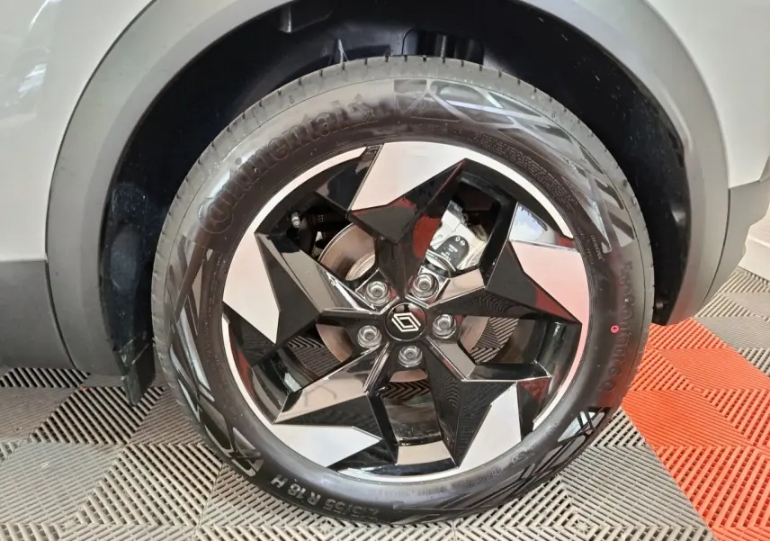 Gros plan sur la roue avant droite blanche du Renault Captur 2025 avec jante noire et argentée au design géométrique.